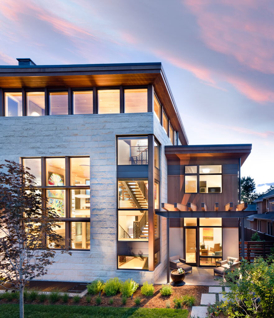 Modern home exterior, showing perimeter windows, white stone, black metal and wood accents.