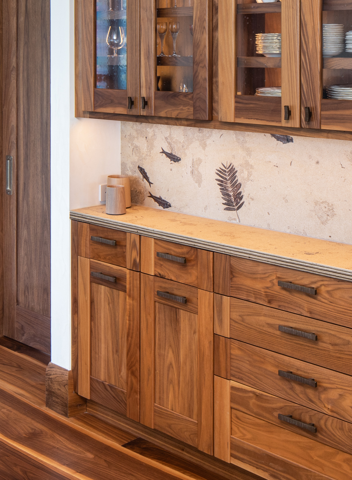 Walnut cabinets with fossil stone backsplash