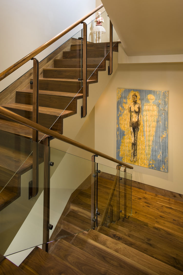 wood staircase with glass railing and artwork on a white wall