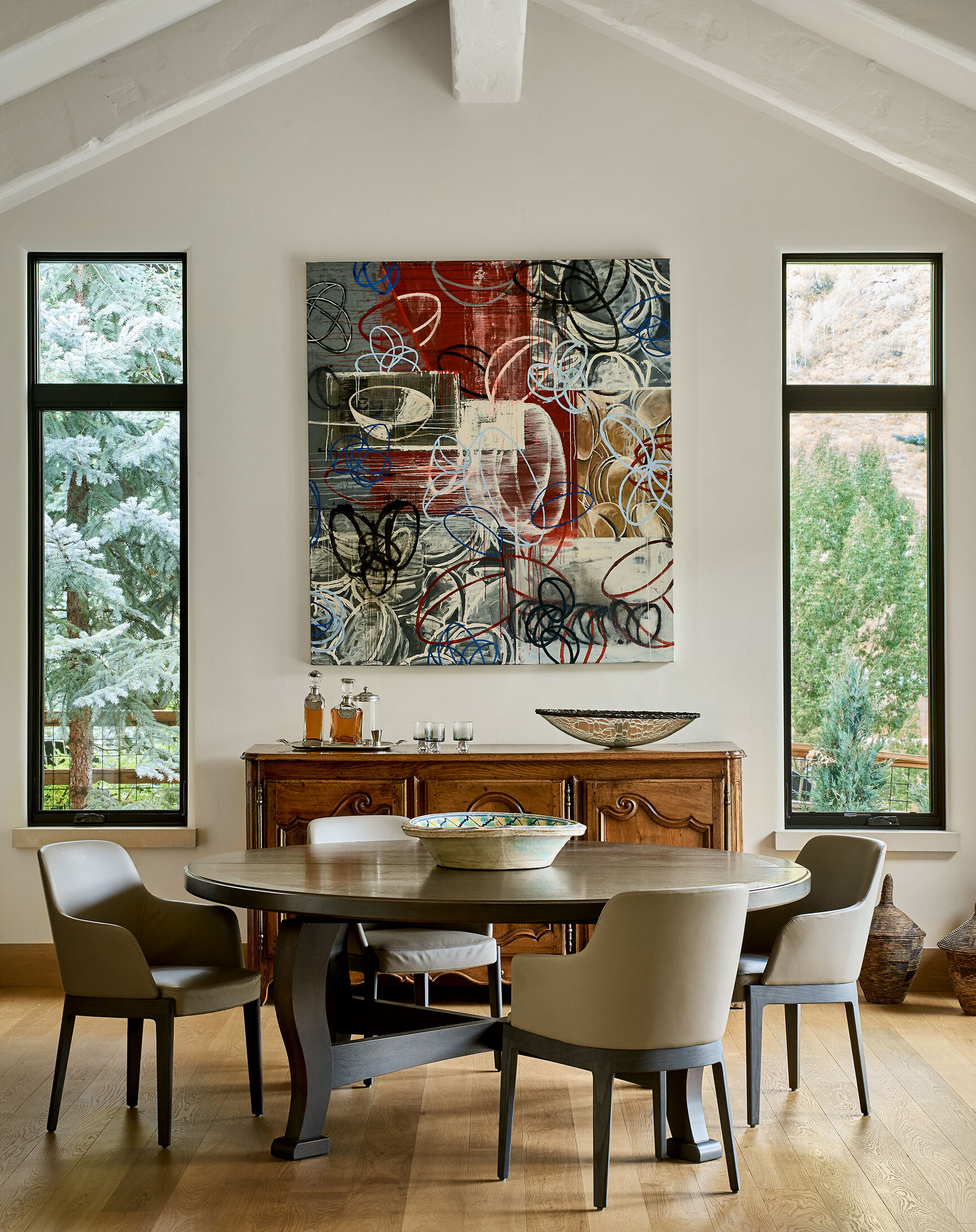 Dining room mixing modern dining chairs and art with an antique sideboard and traditional dining table.