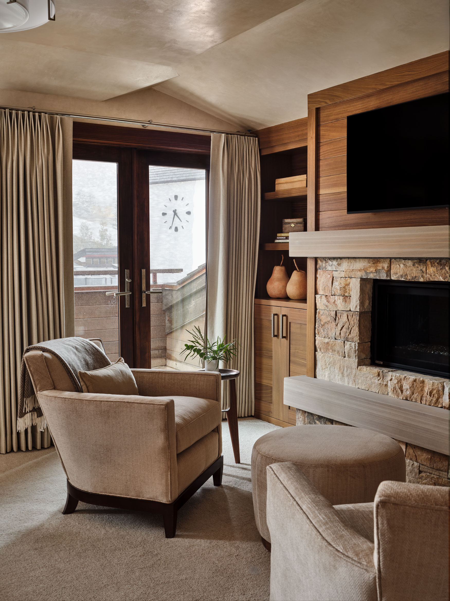 Primary bedroom seating area by fireplace, with glass doors leading to the balcony in the background